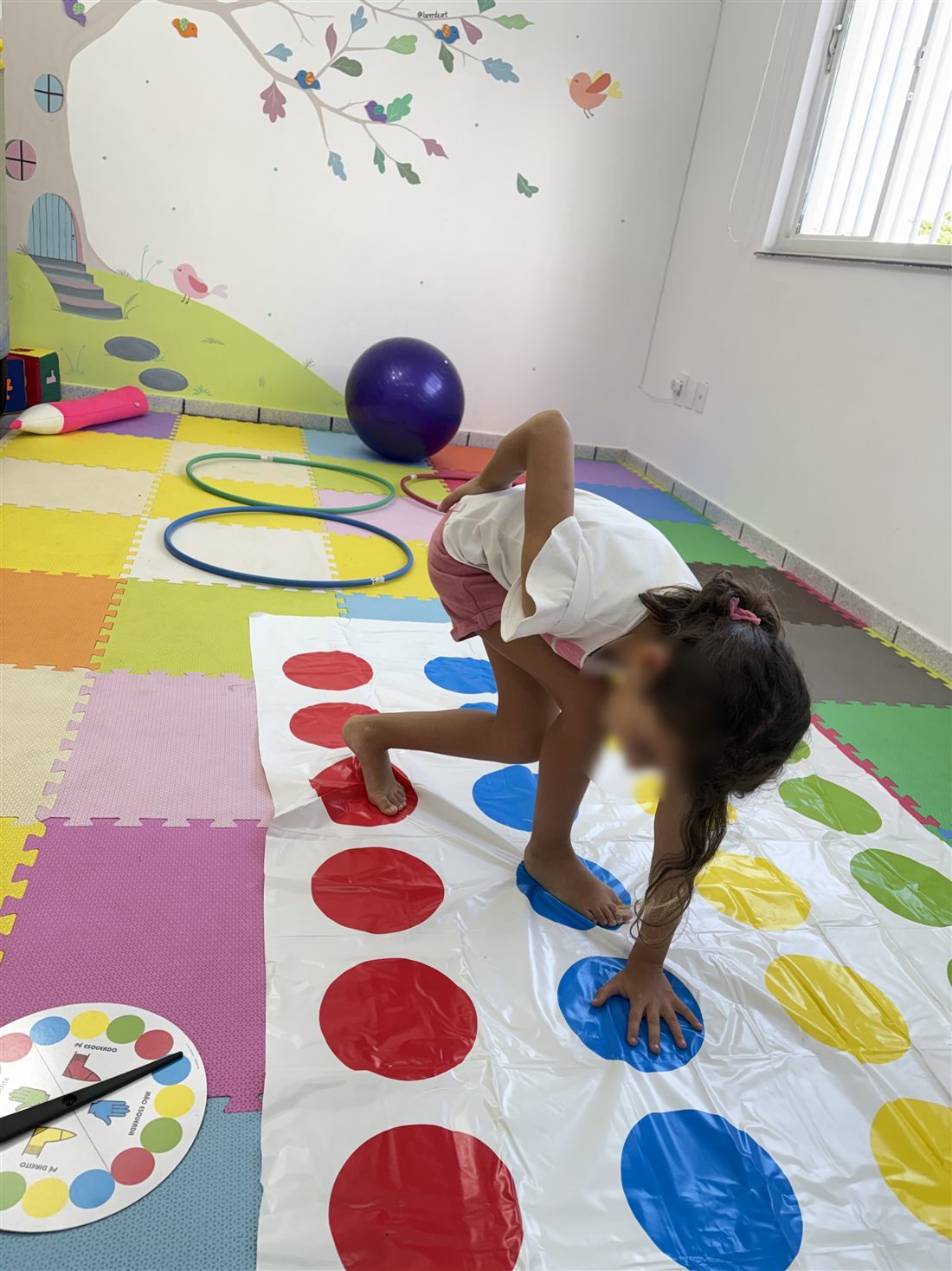Criança em atividade motora com bambolês e circuito colorido